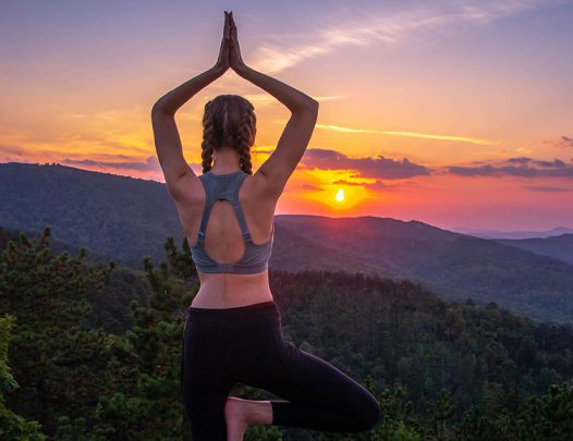 A woman stretching on top of a mountain