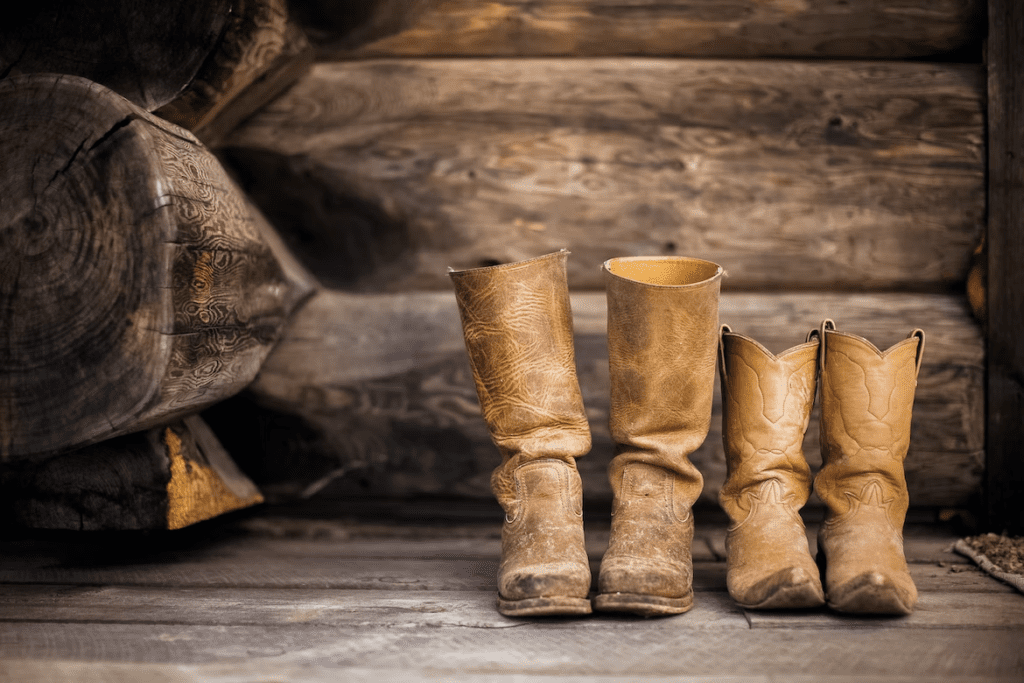 Cowboy and cowgirl boots by a log cabin