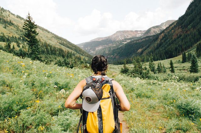 A young woman hiking in a green field