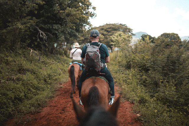 A group of people riding horses on a trail